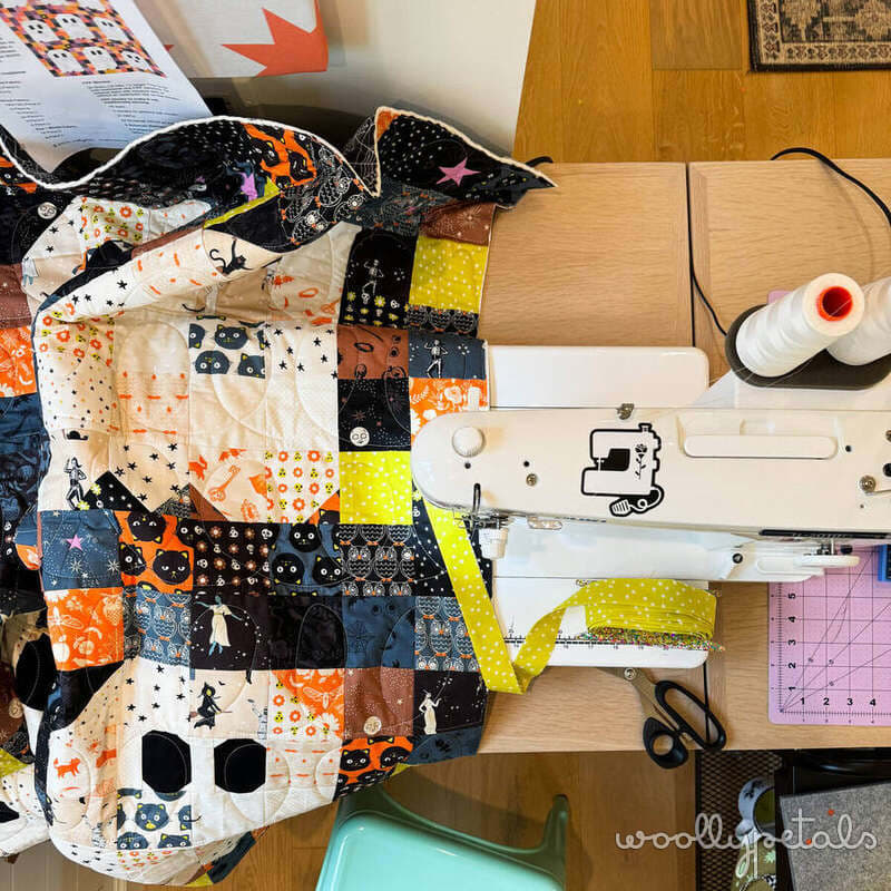 Woollypetals Ghost Party quilt being finished on a sewing machine with batting and backing