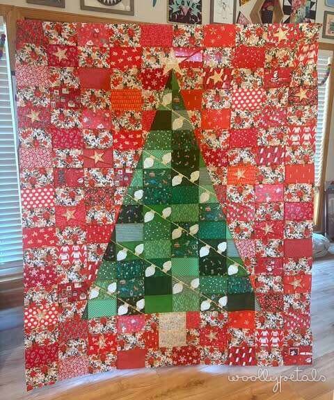 Woollypetals Oh Christmas Tree quilt with green tree blocks and red floral background