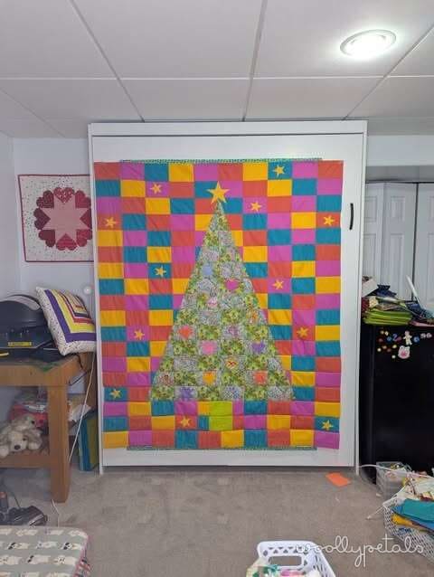 Woollypetals Oh Christmas Tree quilt with colorful patchwork background and floral tree