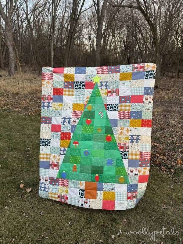 Woollypetals Oh Christmas Tree quilt with green tree and colorful patchwork background