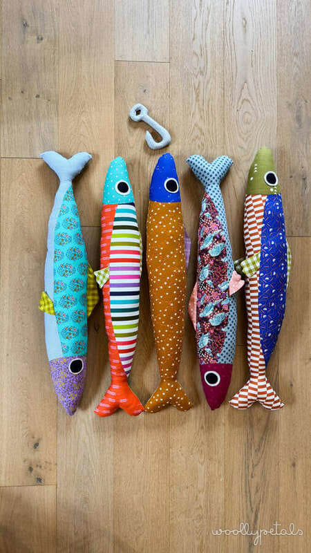 Woollypetals Sardine Pillow pattern in various fabric prints displayed on wood