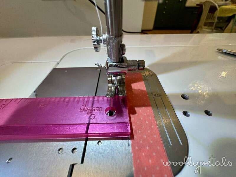 Sewing machine demonstrating scant 1/4 inch seam allowance with pink and red fabric strips