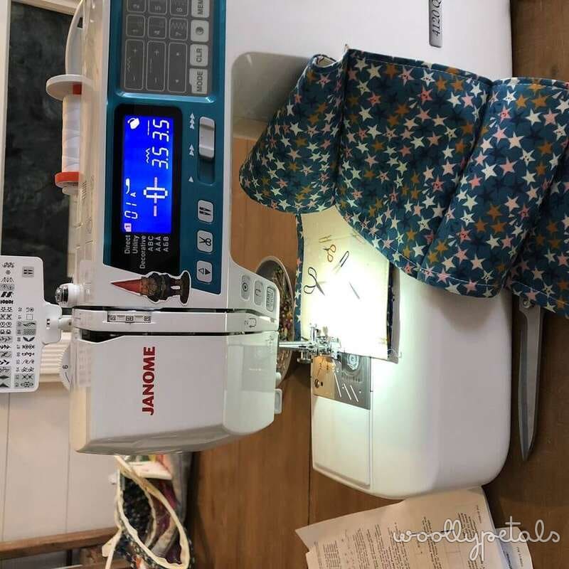 Janome sewing machine with blue digital display and star-patterned fabric
