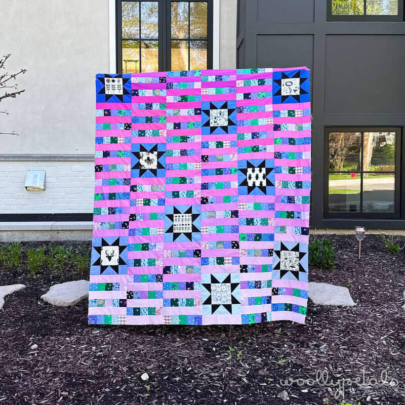 Woollypetals StarBeam quilt in pink, blue, and green fabrics with black and white sawtooth stars