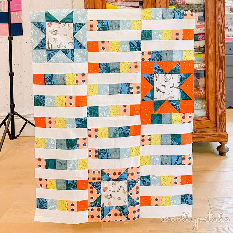 Woollypetals StarBeam quilt throw size with sawtooth stars and strip-pieced columns