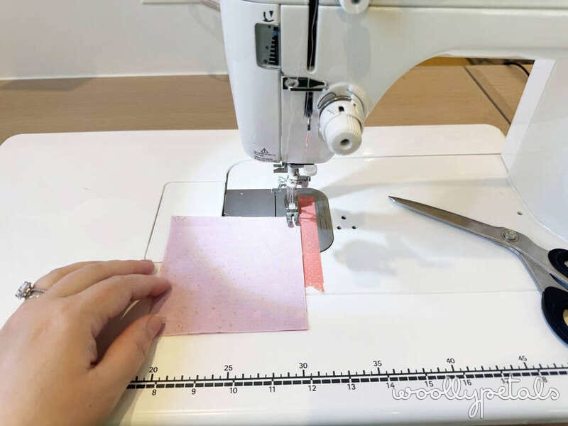 Woollypetals New Star quilt block sewing on machine with pink fabric and ruler
