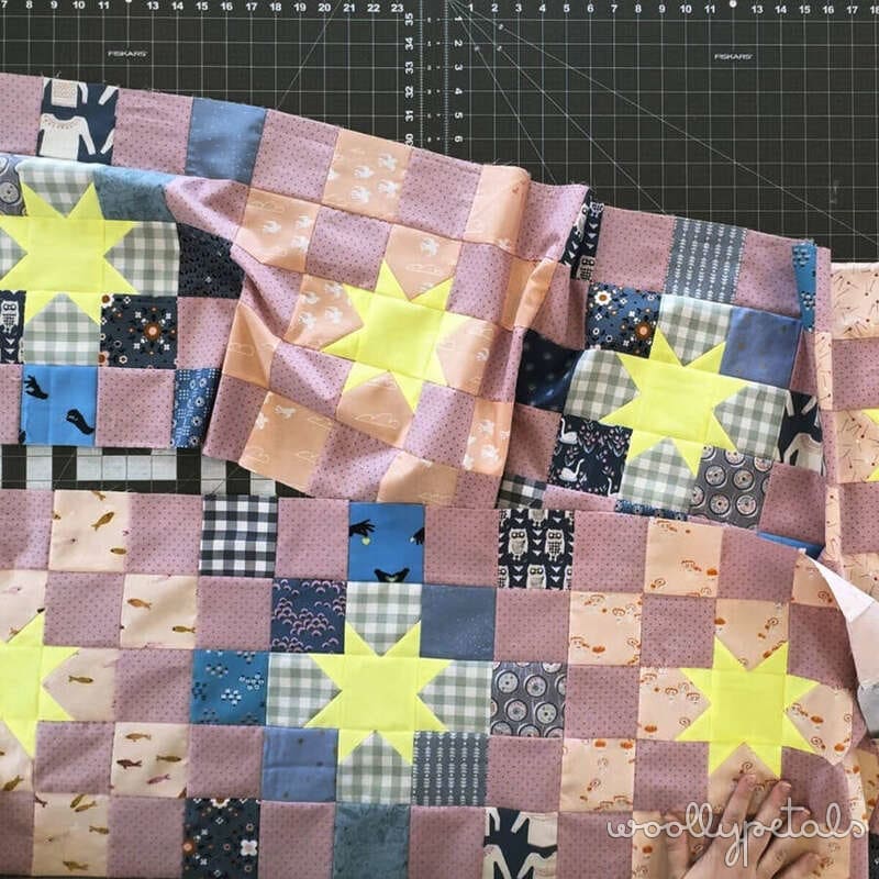 Woollypetals New Star quilt blocks laid out in 4x4 grid with yellow stars and colorful fabric patches