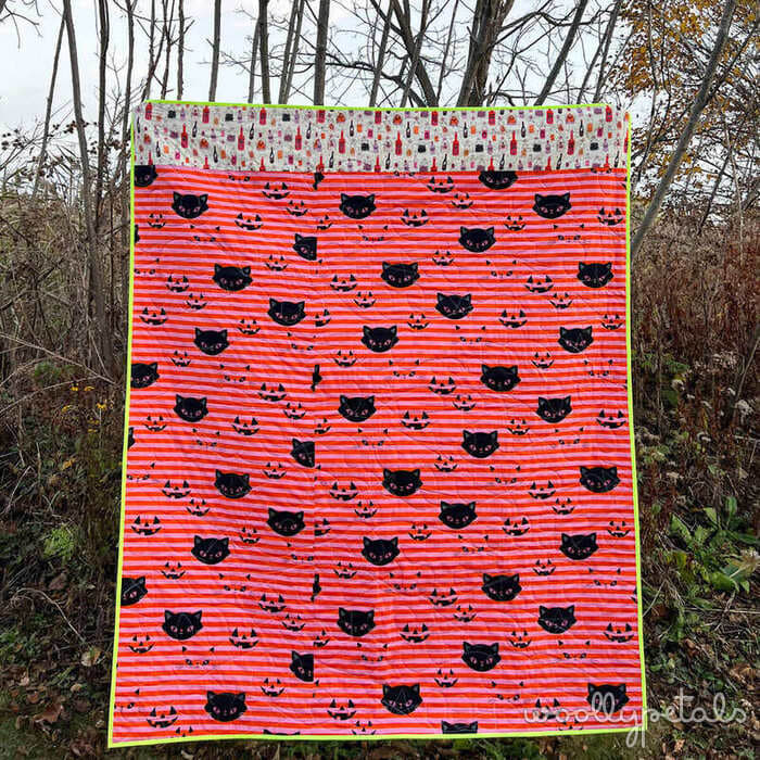Woollypetals Halloween quilt with black cats and orange pumpkins on red striped backing