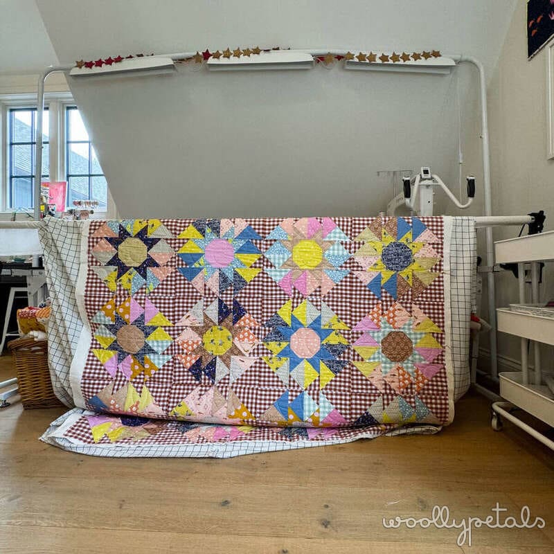 Woollypetals colorful star quilt with gingham and patchwork fabrics on display frame