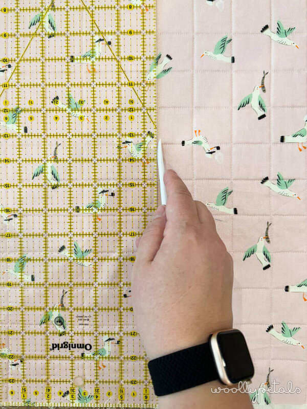 Quilting ruler and fabric showing straight line quilting pattern placement