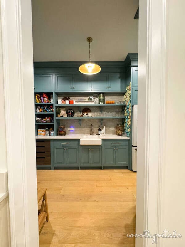 Kitchen with teal cabinetry, open shelving, and farmhouse sink