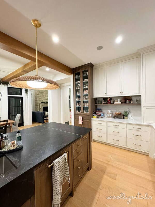 Modern kitchen with dark island, white cabinetry, and brass pendant lighting