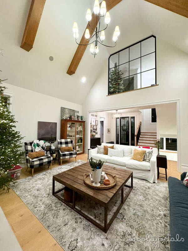 Bright modern living room with vaulted ceilings, wooden beams, and large black-framed window