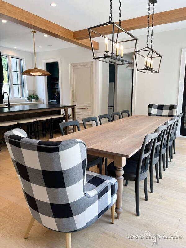 Modern dining room with wooden table, black chairs, and black and white buffalo check upholstered chair