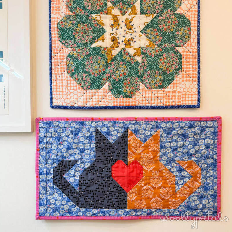 Mini quilts from Woollypetals 2024 Swap displayed on white wall