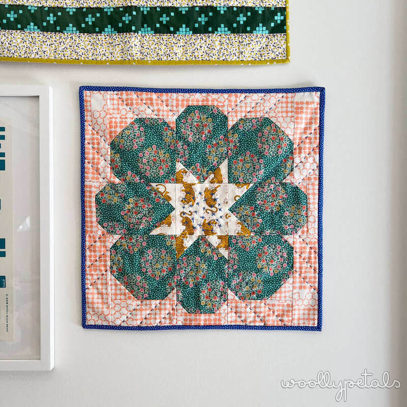 Mini quilt with green flower petals and orange gingham border