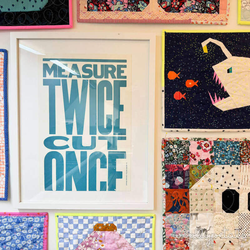 Framed typography print reading 'Measure Twice Cut Once' in teal blue