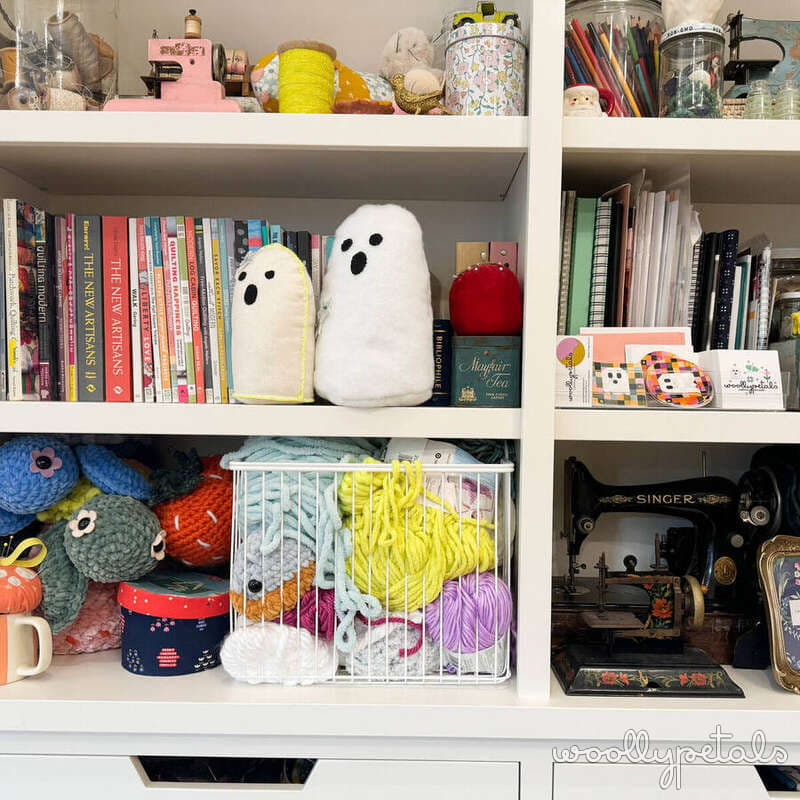 Organized craft shelving with books, yarn, sewing machine, and ghost decorations