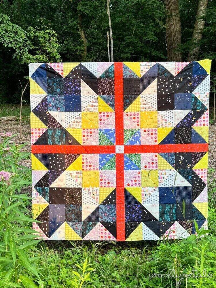 Woollypetals Starfy quilt with colorful star blocks and red cross border