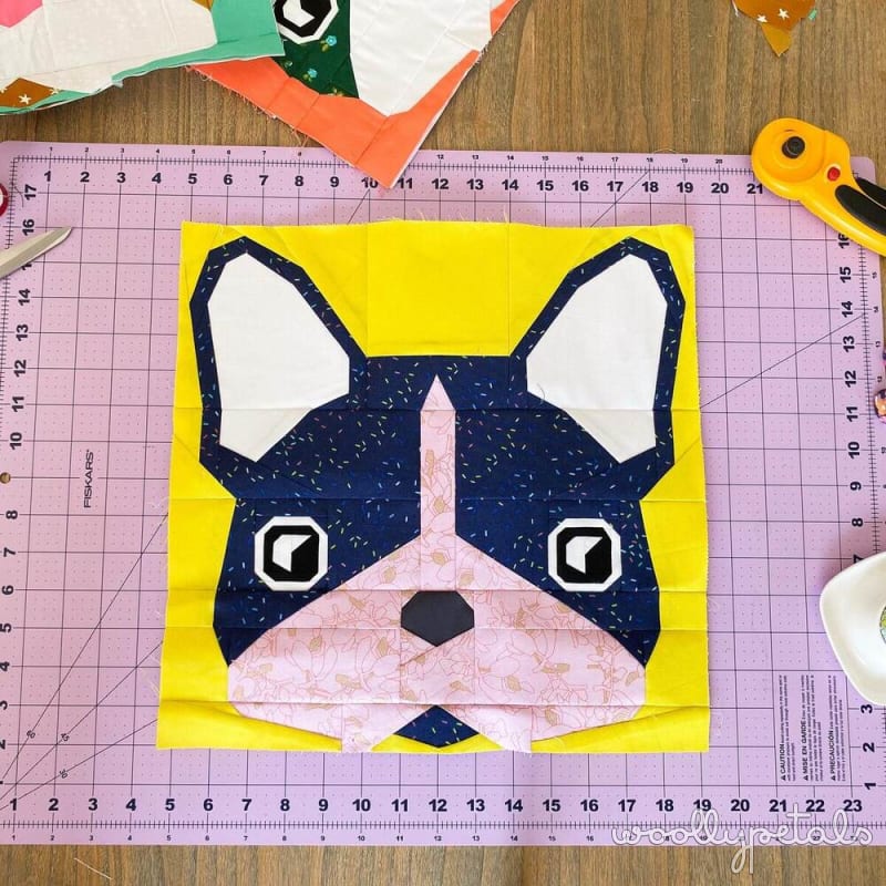 Woollypetals Beatrice Bulldog FPP quilt block with navy, pink, and white fabrics on yellow background