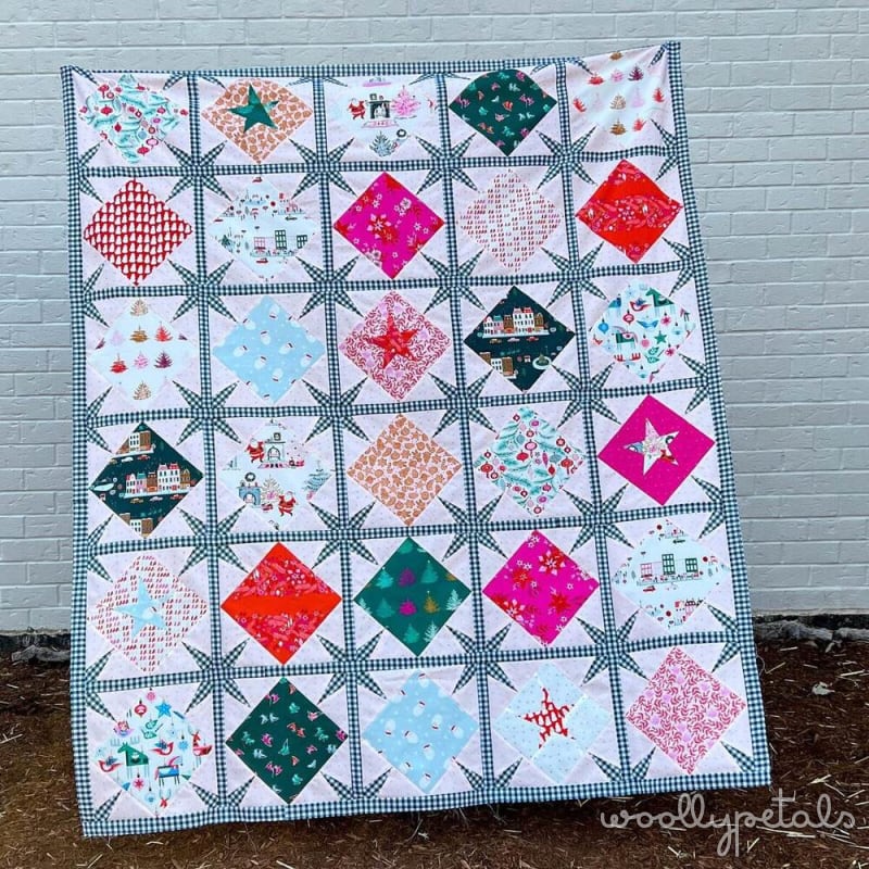 Woollypetals Sparked Quilt in red, green, and pink fabrics with navy gingham border
