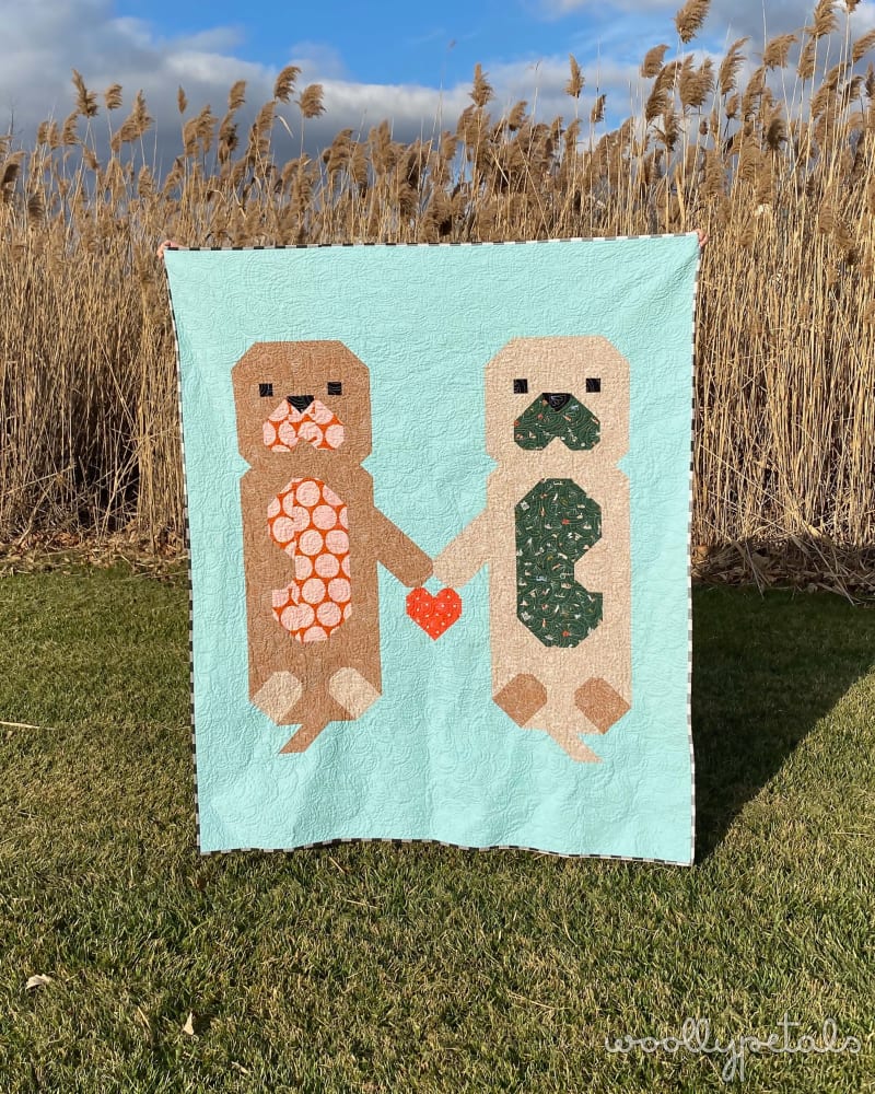 Woollypetals Don't Let Go quilt displayed outdoors with light blue background